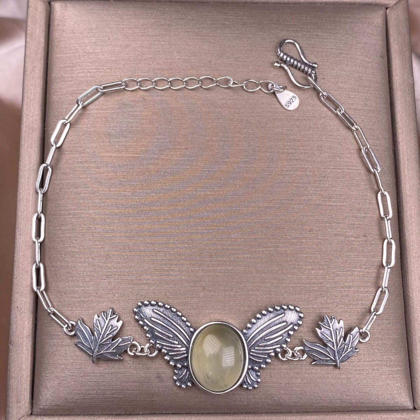 Silver bracelet with leaf designs and a central stone grape stone