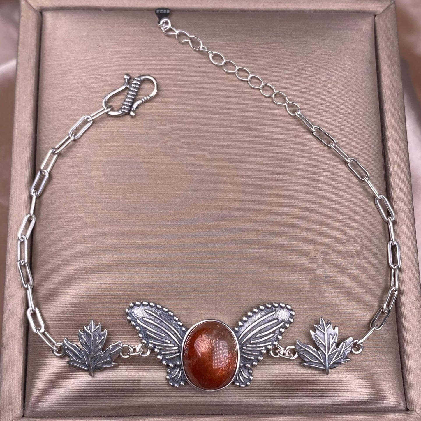 Silver bracelet with leaf designs and a central brown stone golden sun stone